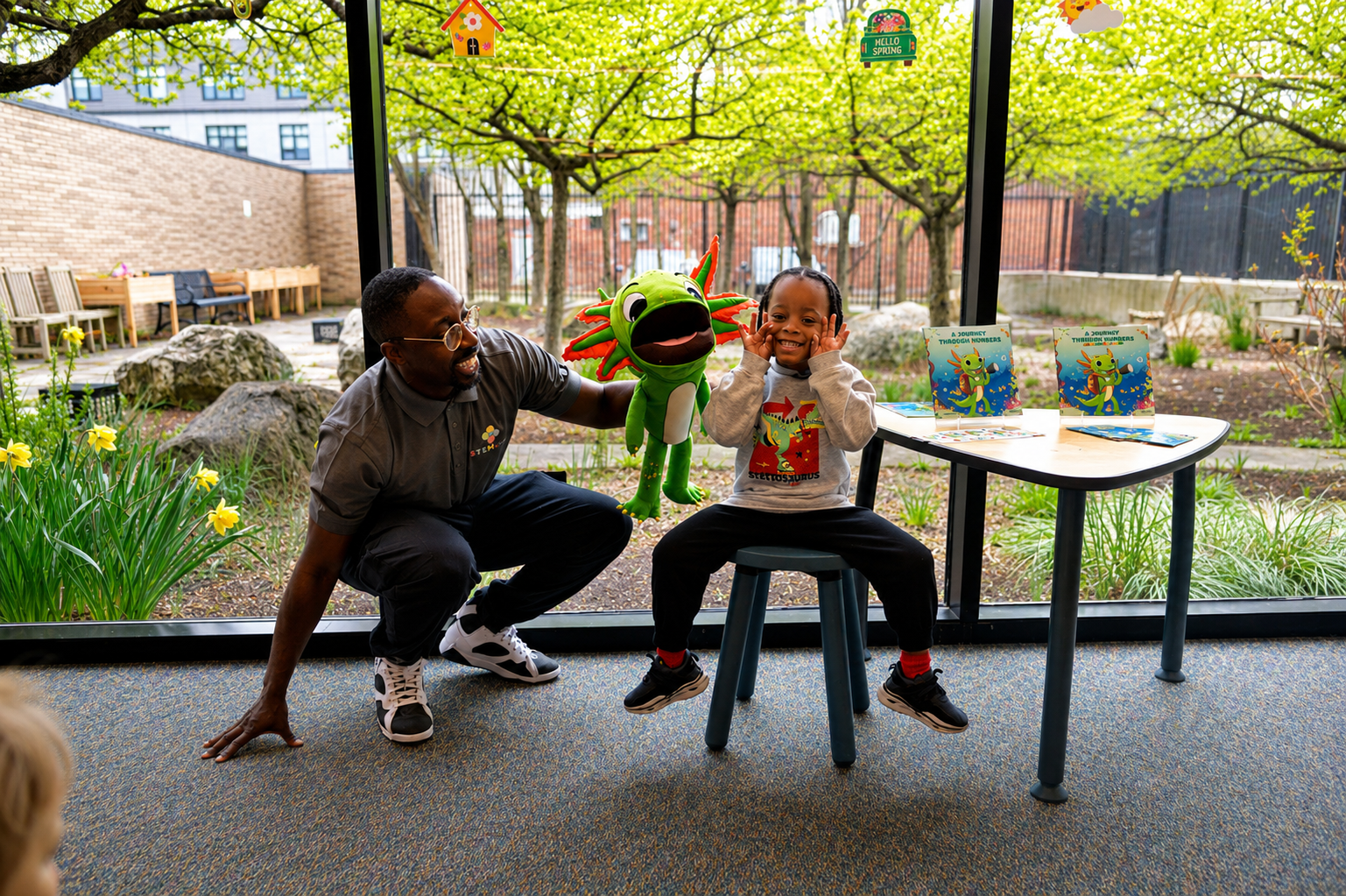 Child joyfully meeting Axl the puppet at a STEMtacular storytime event
